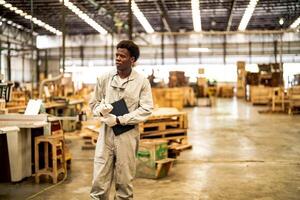 African man workers engineering standing with confidence with working suite dress and hand glove in front machine. Concept of smart industry worker operating. Wood factory produce wood palate. photo