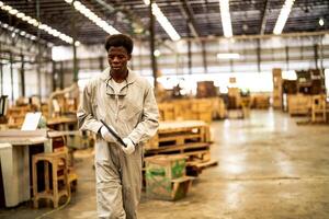 African man workers engineering standing with confidence with working suite dress and hand glove in front machine. Concept of smart industry worker operating. Wood factory produce wood palate. photo