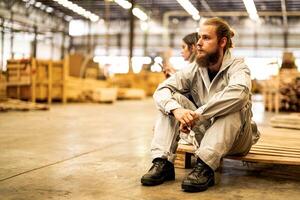 man workers engineering sitting with confidence with working suite dress and hand glove in front machine. Concept of smart industry worker operating. Wood factory produce wood palate. photo