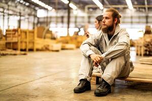 man workers engineering sitting with confidence with working suite dress and hand glove in front machine. Concept of smart industry worker operating. Wood factory produce wood palate. photo