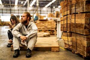 man workers engineering sitting with confidence with working suite dress and hand glove in front machine. Concept of smart industry worker operating. Wood factory produce wood palate. photo