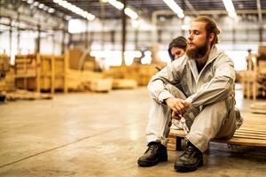 man workers engineering sitting with confidence with working suite dress and hand glove in front machine. Concept of smart industry worker operating. Wood factory produce wood palate. photo