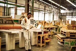 African man workers engineering standing with confidence with working suite dress and hand glove in front machine. Concept of smart industry worker operating. Wood factory produce wood palate. photo