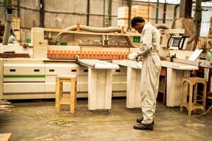 African man workers engineering standing with confidence with working suite dress and hand glove in front machine. Concept of smart industry worker operating. Wood factory produce wood palate. photo