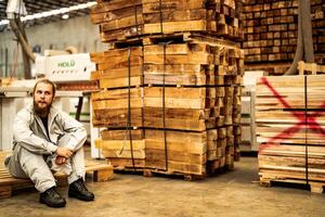 man workers engineering sitting with confidence with working suite dress and hand glove in front machine. Concept of smart industry worker operating. Wood factory produce wood palate. photo