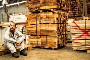 man workers engineering sitting with confidence with working suite dress and hand glove in front machine. Concept of smart industry worker operating. Wood factory produce wood palate. photo