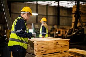 equipo trabajador carpintero vistiendo la seguridad uniforme y difícil sombrero trabajando y comprobación el calidad de de madera productos a taller fabricación. hombre y mujer trabajadores madera en oscuro almacén industria. foto