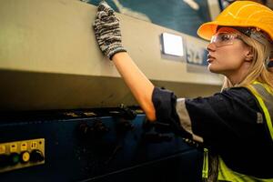 Factory engineer woman standing confidence to control panel switch. Worker works at heavy machine at industry factory. with machinery equipment plant technology. smart industry worker operating. photo