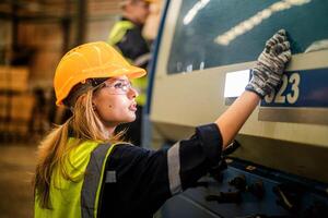 Factory engineer woman standing confidence to control panel switch. Worker works at heavy machine at industry factory. with machinery equipment plant technology. smart industry worker operating. photo