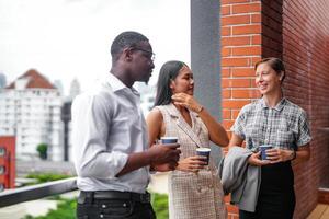 team of business people smart man and women stand at outdoor terrace building and talk together with breakfast food and coffee on the hand in good feeling with city space building. business morning. photo