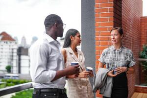 equipo de negocio personas inteligente hombre y mujer estar a al aire libre terraza edificio y hablar juntos con desayuno comida y café en el mano en bueno sensación con ciudad espacio edificio. negocio Mañana. foto