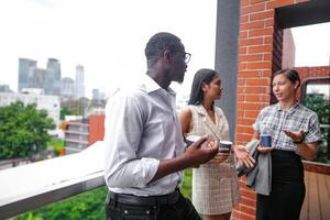 equipo de negocio personas inteligente hombre y mujer estar a al aire libre terraza edificio y hablar juntos con desayuno comida y café en el mano en bueno sensación con ciudad espacio edificio. negocio Mañana. foto