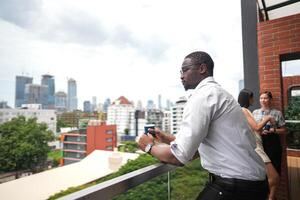 African business smart man stands at outdoor terrace building. people with on hand in good feeling with city space building. relaxing of people business morning. photo