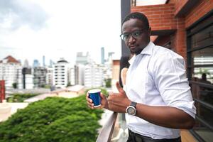 African business smart man stands at outdoor terrace building. people with on hand in good feeling with city space building. relaxing of people business morning. photo