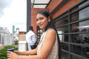 African business smart woman stands at outdoor terrace building. people with on hand in good feeling with city space building. relaxing of people business morning. photo