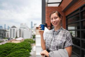 African business smart woman stands at outdoor terrace building. people with on hand in good feeling with city space building. relaxing of people business morning. photo