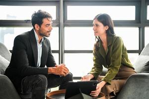 negocio personas teniendo divertido y chateando a lugar de trabajo oficina. masculino y hembra colega disfrutar reunión a co trabajando espacio. colegas que se discute acerca de el proyecto en el oficina. foto