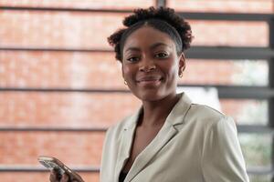 Portrait business african woman smiling and using smart mobile phone. headshot of an african american businesswoman. photo