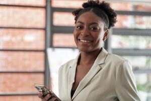 Portrait business african woman smiling and using smart mobile phone. headshot of an african american businesswoman. photo