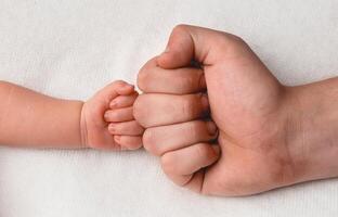 mano de recién nacido hijo y papá cerca arriba en blanco antecedentes foto