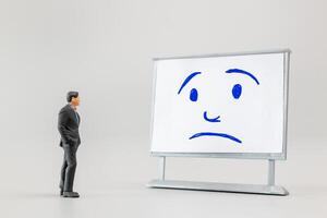 Miniature people, A dejected businessman is positioned in front of a white board, Blue monday concept photo