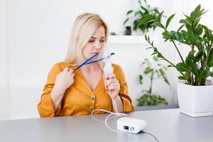 mujer hace inhalación nebulizador a hogar. participación un máscara nebulizador inhalando vapores rociar el medicación dentro tu livianos enfermo paciente. autotratamiento de el respiratorio tracto utilizando inhalación nebulizador foto