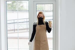 mujer vistiendo protector máscara en pie en café durante covid-19 previniendo. foto