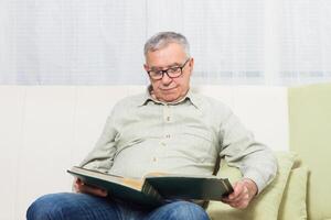 Senior man is watching his photo album and he is feeling sadnes