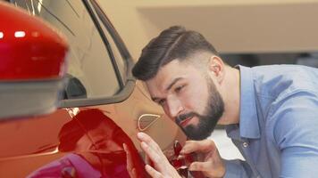 Handsome bearded man examining red automobile at the dealership video