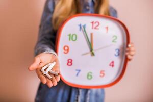 Woman holding broken cigarettes and clock in front of the wall.Quitting smoking concept. photo