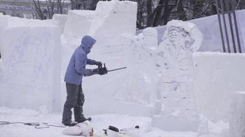 View of sculptor carving ice. Movement. Cut ice with a chainsaw. Cut and make snow sculpture. Chopping iced water with an axe. Ice Sculpture Carving. V-LOG photo