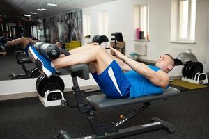 un muscular entrenador en gimnasio es comprometido en Deportes en simuladores. capacitación, entrenamiento, peso pérdida programa. el hombre en simuladores. Copiar espacio, interior concepto, sano activo estilo de vida. foto