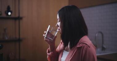 antal fot av ung asiatisk kvinna dryck vatten i kök på hem, frisk mat och wellness begrepp video