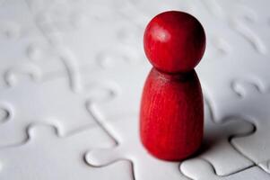 A single red wooden doll on jigsaw puzzle photo