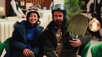 POV of people talking on videocall and wearing winter jackets with helmets, tourists preparing to go skiing on mountain slopes. Hotel guests answering call on video conference. Tripod shot.