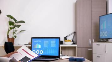 Man in his living room checking company data on animated charts that are displaying on the computer screen. Dolly slider 4K footage video