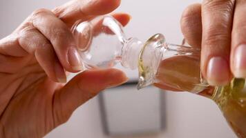 Down view of a bottle with oil opening and the oil drips in a salad bowl. Unusual angle video