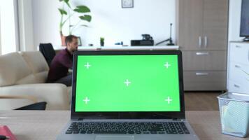 Laptop with green screen chroma on it in the middle of living room. The screen is with markers for traking. Dolly slider 4K footage video