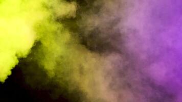 Dense, abstract and colorful smoke clouds over a black background in studio video