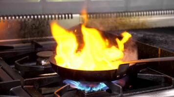 Frying a piece of beef meat on a pan with open fire. Close up slow motion footage video