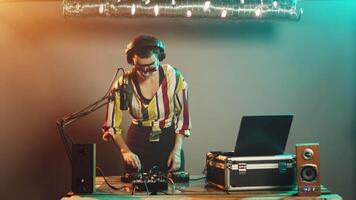 DJ musician using turntables to mix techno sounds, producing music at professional mixer with electronics bass buttons. Woman artist doing remix stereo performance at club. Tripod shot. video