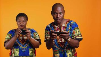 Ethnic couple having fun with mobile videogames on phone, participating in online gaming tournament on camera. African american man and woman playing in game contest on smartphone. video