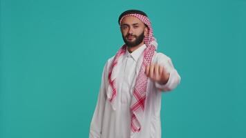 Middle eastern person does stop sign with palm up, expressing refusal and denial on studio camera. Young man presenting rejection symbol, being displeased and disappointed. video