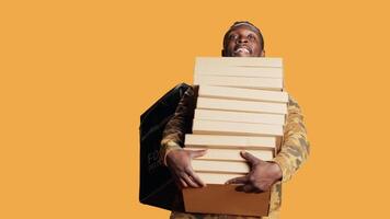 ung deliveryman ger enorm stack av pizza lådor till klient, leverera stor snabb mat beställa och bärande hämtmat ryggsäck. manlig modell Framställ som leverans person med ta ut mat. video
