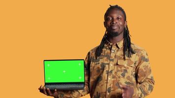 Person having laptop with greenscreen display on camera, posing with blank chromakey layout on wireless pc. Young man presenting computer with isolated copyspace screen in studio. video