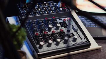 Close up shot of professional analog mixer with mixing channels, onboard effects and quality microphone able to produce impeccable sound during podcast recording in dimly lit studio video