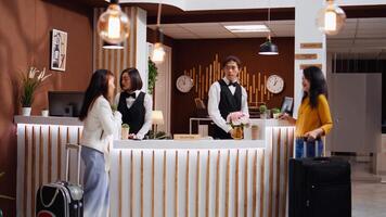 Employees team greeting two women at five star hotel, providing luxury concierge services helping with luggage after check in. Girlfriends travelling on vacation at holiday resort, welcome tourists. video