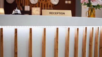 Reception sign placed on front desk in hotel lobby indicating place to book rooms and do check in process for accommodation. Empty resort hallway used to greet customers. Close up. video