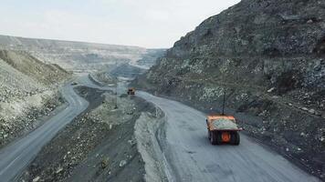 Top view of quarry dump truck. Dump truck traveling on dusty roads of open pit extraction of minerals. Heavy transport in extractive industry video