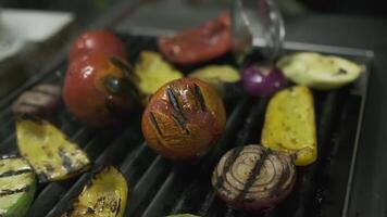 The chef turns over the vegetables that are fried on the grill with metal tongs video